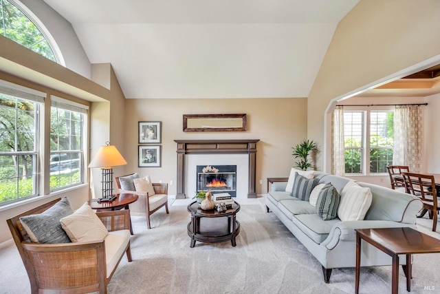 living area featuring a glass covered fireplace, carpet flooring, and high vaulted ceiling