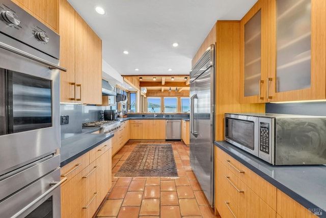 kitchen featuring stainless steel appliances, dark countertops, light tile patterned flooring, and light brown cabinetry