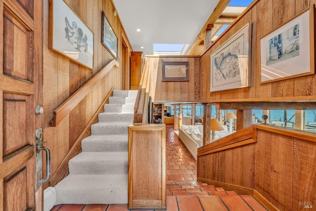 stairway with recessed lighting, wood walls, a skylight, and brick floor