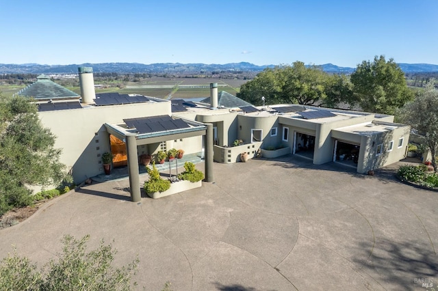 view of front of home featuring solar panels, fence, a mountain view, and stucco siding