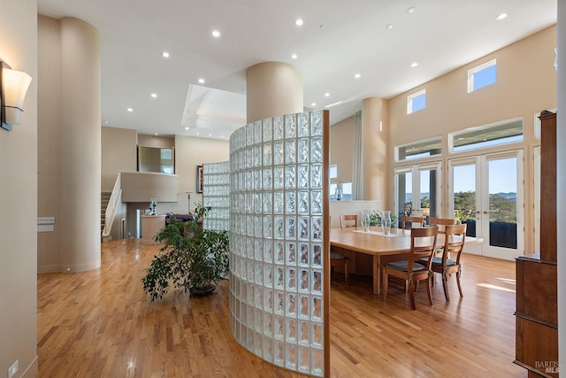 dining area featuring recessed lighting, light wood-style flooring, french doors, and a high ceiling