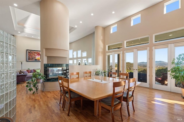 dining area featuring a multi sided fireplace, french doors, a high ceiling, wood finished floors, and a mountain view