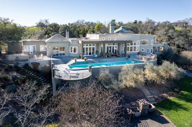 back of property featuring an outdoor pool, french doors, a patio, and a chimney