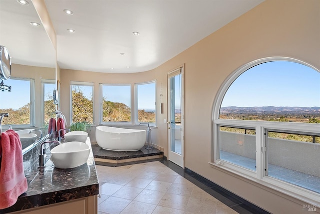 bathroom with vanity, a freestanding tub, plenty of natural light, and recessed lighting