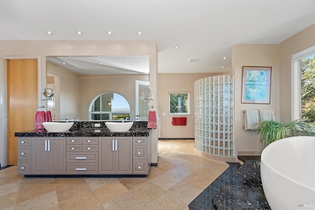 full bath with recessed lighting, a freestanding bath, and a sink