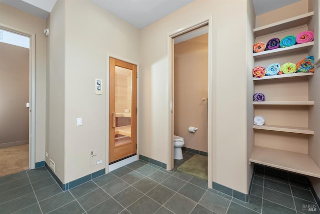bathroom featuring tile patterned flooring, toilet, and baseboards
