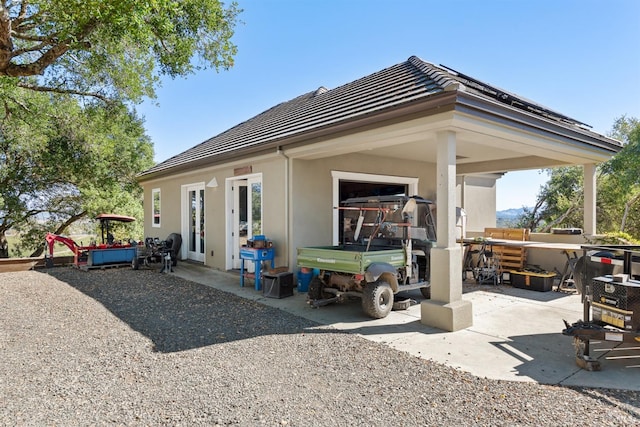 rear view of property featuring a patio area, stucco siding, and a tiled roof