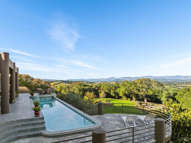 view of swimming pool featuring a patio area, a mountain view, and a wooded view