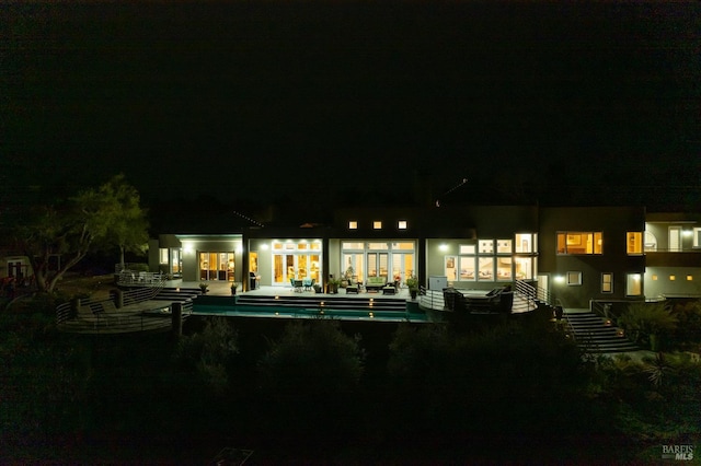 back of house at twilight featuring an outdoor pool and a patio