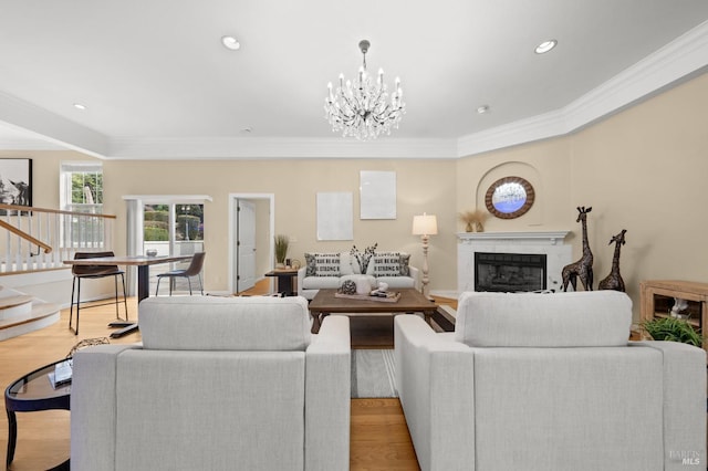 living area featuring a high end fireplace, an inviting chandelier, ornamental molding, and light wood-style flooring