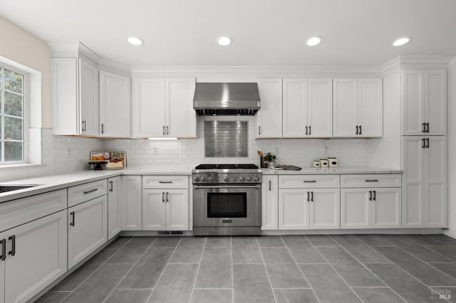 kitchen featuring high end stainless steel range, backsplash, extractor fan, and white cabinetry
