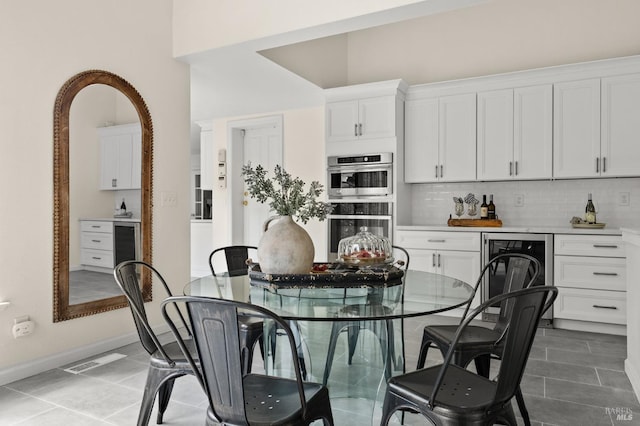 dining room featuring baseboards, visible vents, beverage cooler, and tile patterned floors
