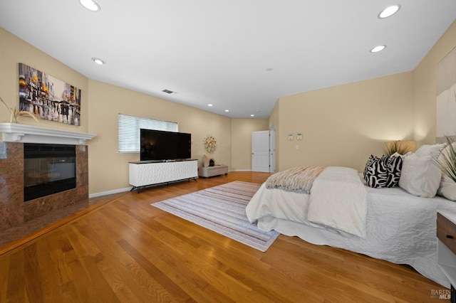 bedroom featuring a fireplace with flush hearth, wood finished floors, recessed lighting, and visible vents