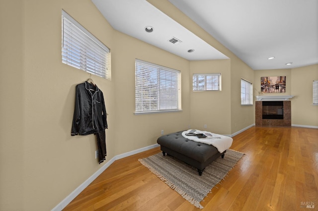 living area featuring light wood finished floors, baseboards, visible vents, a glass covered fireplace, and recessed lighting