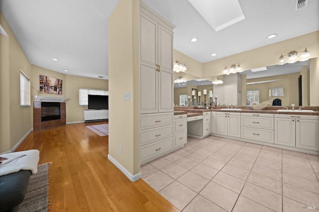 bathroom with a fireplace with flush hearth, plenty of natural light, a skylight, and a sink