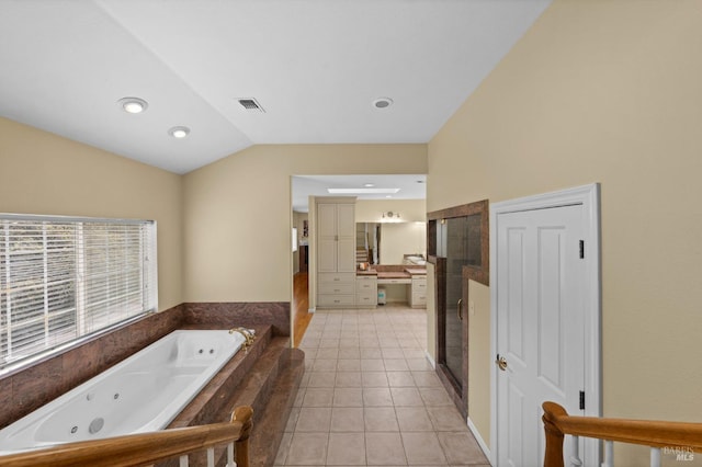 bathroom with lofted ceiling, tile patterned floors, visible vents, vanity, and a tub with jets