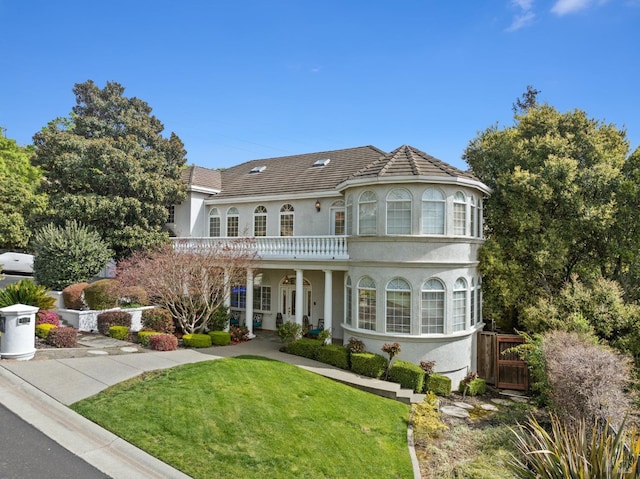 view of front of property featuring fence, a tiled roof, a front lawn, and stucco siding