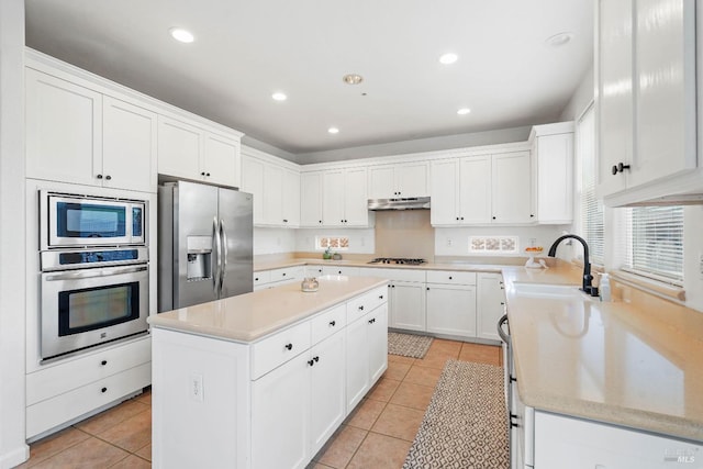 kitchen featuring under cabinet range hood, stainless steel appliances, a center island, and light tile patterned floors