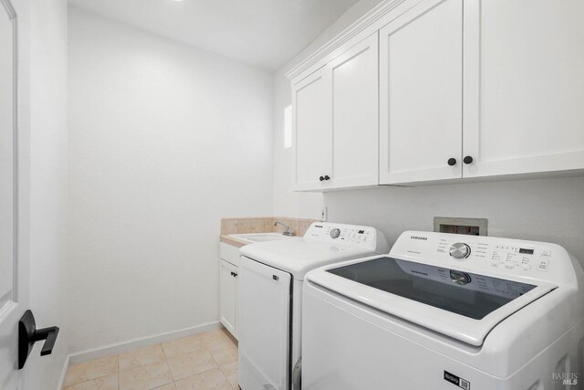 washroom featuring baseboards, light tile patterned floors, cabinet space, independent washer and dryer, and a sink