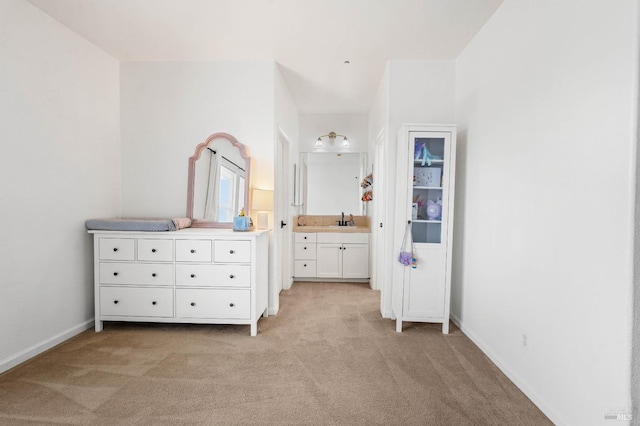 unfurnished bedroom featuring light colored carpet, ensuite bath, baseboards, and a sink