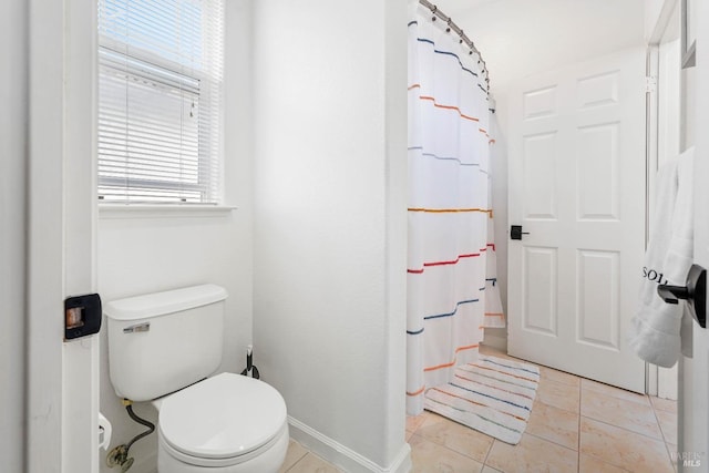 bathroom featuring tile patterned flooring, toilet, a shower with shower curtain, and baseboards