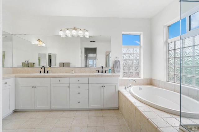 bathroom with tile patterned flooring, double vanity, a bath, and a sink
