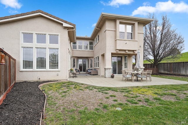 back of property featuring stucco siding, a fenced backyard, a yard, a balcony, and a patio area