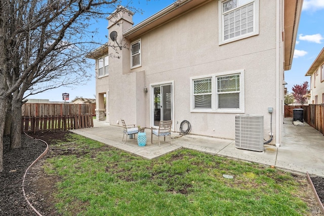 rear view of property featuring stucco siding, cooling unit, a lawn, a fenced backyard, and a patio area