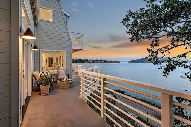 balcony at dusk with a fire pit and a water view