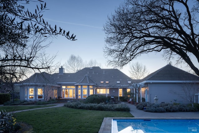 1706 Garnett Creek Ct, Calistoga, CA 94515 - back of house at dusk with a chimney, a yard, and an outdoor pool