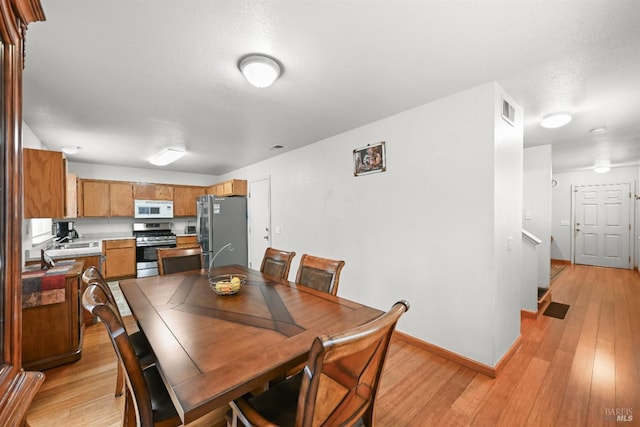 dining room with visible vents, baseboards, and light wood-style floors