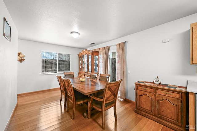 dining area with light wood-type flooring, baseboards, and visible vents