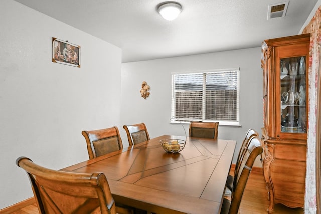 dining area featuring visible vents, light wood-style flooring, and baseboards