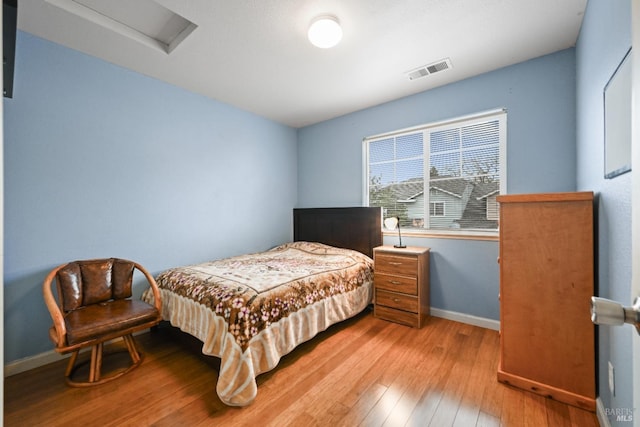 bedroom featuring baseboards, visible vents, attic access, and light wood-style floors
