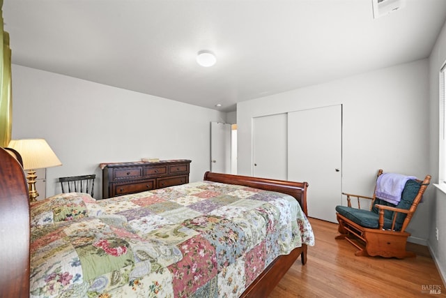 bedroom featuring a closet, visible vents, and wood finished floors