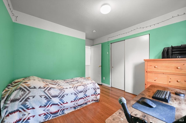 bedroom with wood finished floors and a closet