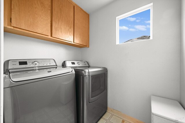 washroom featuring baseboards, cabinet space, and washer and clothes dryer