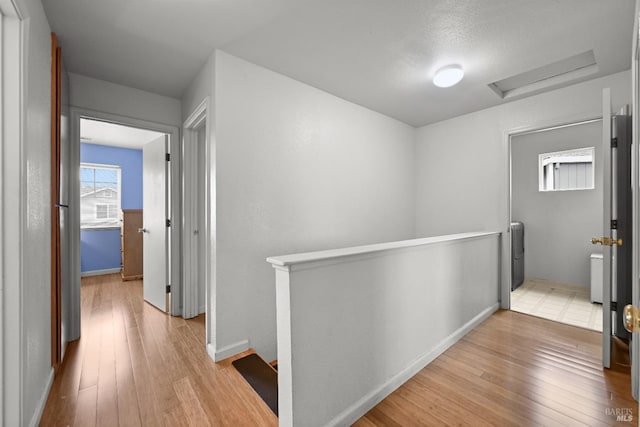 hall with attic access, hardwood / wood-style flooring, an upstairs landing, and baseboards