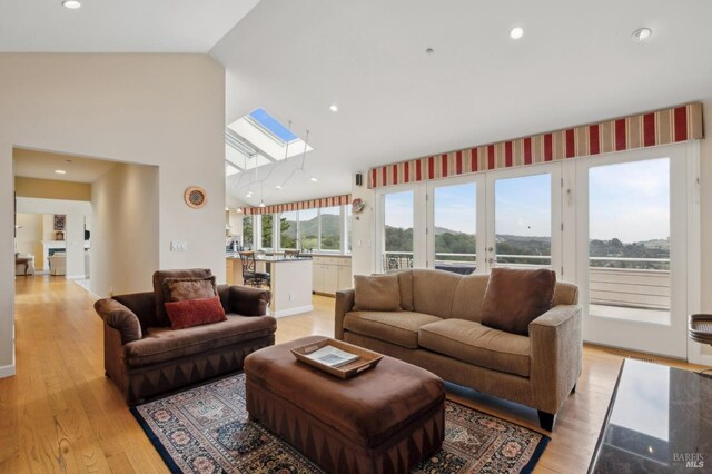 living area with a skylight, light wood finished floors, and recessed lighting