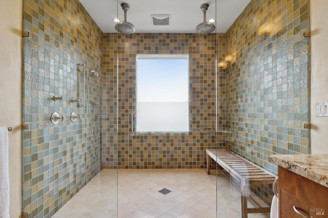 full bathroom featuring a tile shower, tile patterned floors, and visible vents