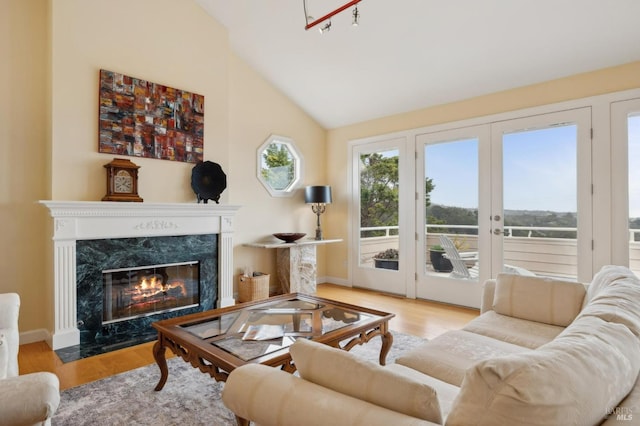 living room with wood finished floors, french doors, vaulted ceiling, and a premium fireplace