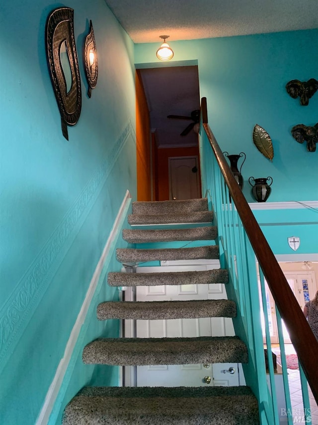 stairway featuring ceiling fan