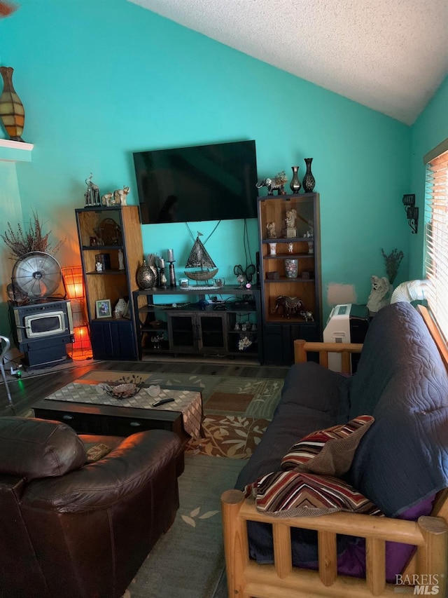 living room featuring wood finished floors, a textured ceiling, a wood stove, and vaulted ceiling