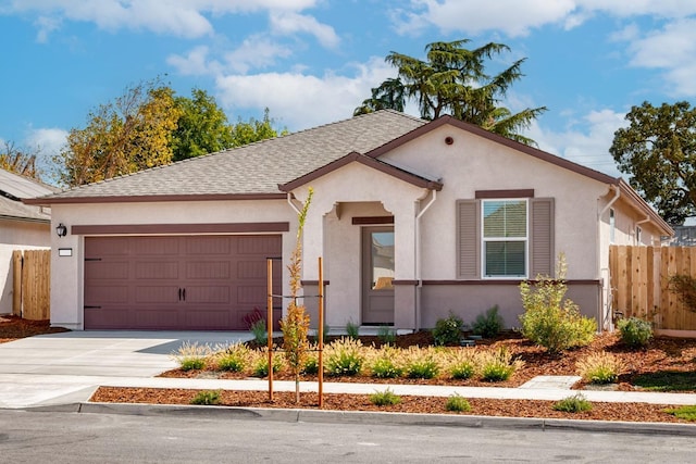 view of front of home featuring roof with shingles, concrete driveway, stucco siding, an attached garage, and fence