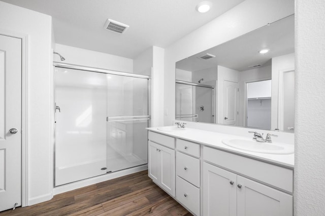 full bath with a stall shower, visible vents, wood finished floors, and a sink