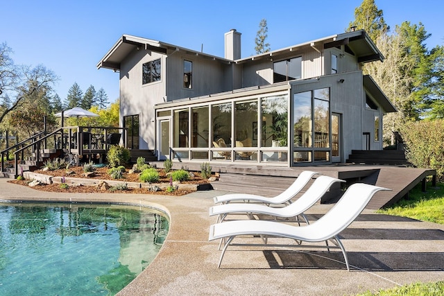 3651 Bones Rd, Sebastopol, CA 95472 - back of property featuring a wooden deck, an outdoor pool, a chimney, a sunroom, and a patio