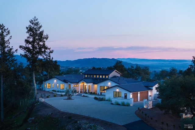 view of front of property featuring a mountain view, curved driveway, an attached garage, and stucco siding