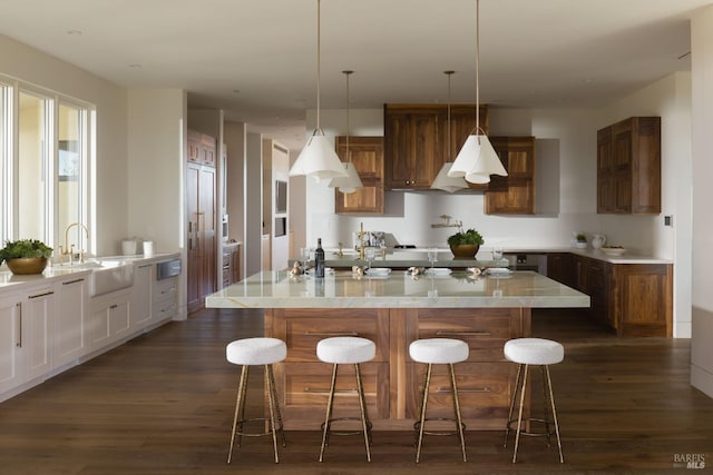 kitchen featuring dark wood-style floors, a breakfast bar, a large island, and a sink