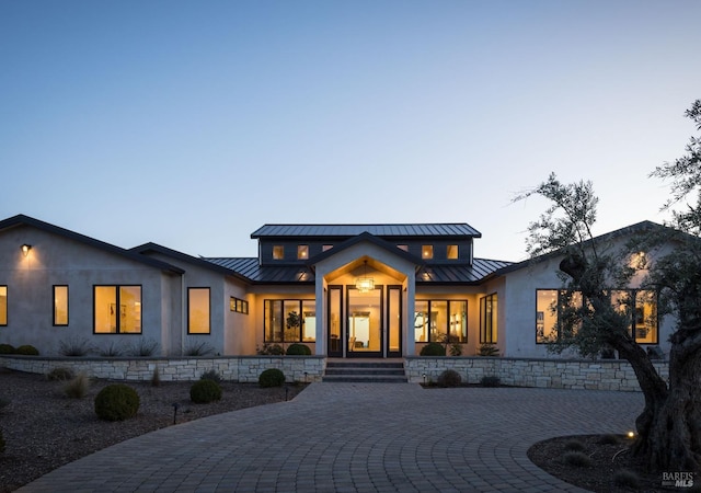 view of front of house featuring a standing seam roof, a porch, stucco siding, and metal roof