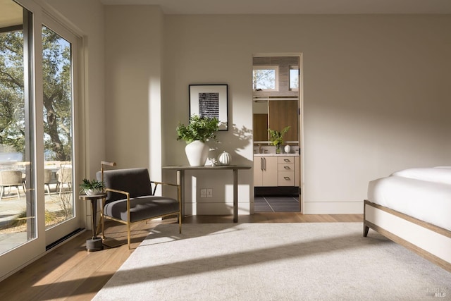 bedroom with baseboards, wood finished floors, and ensuite bathroom